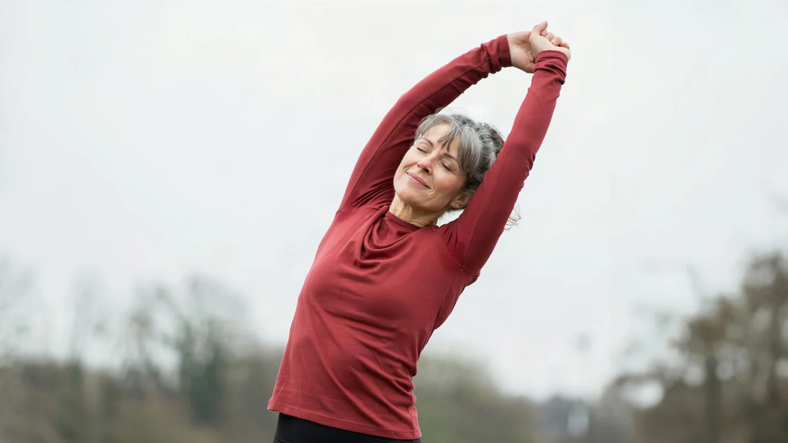 A woman in her fifties stretching outdoors