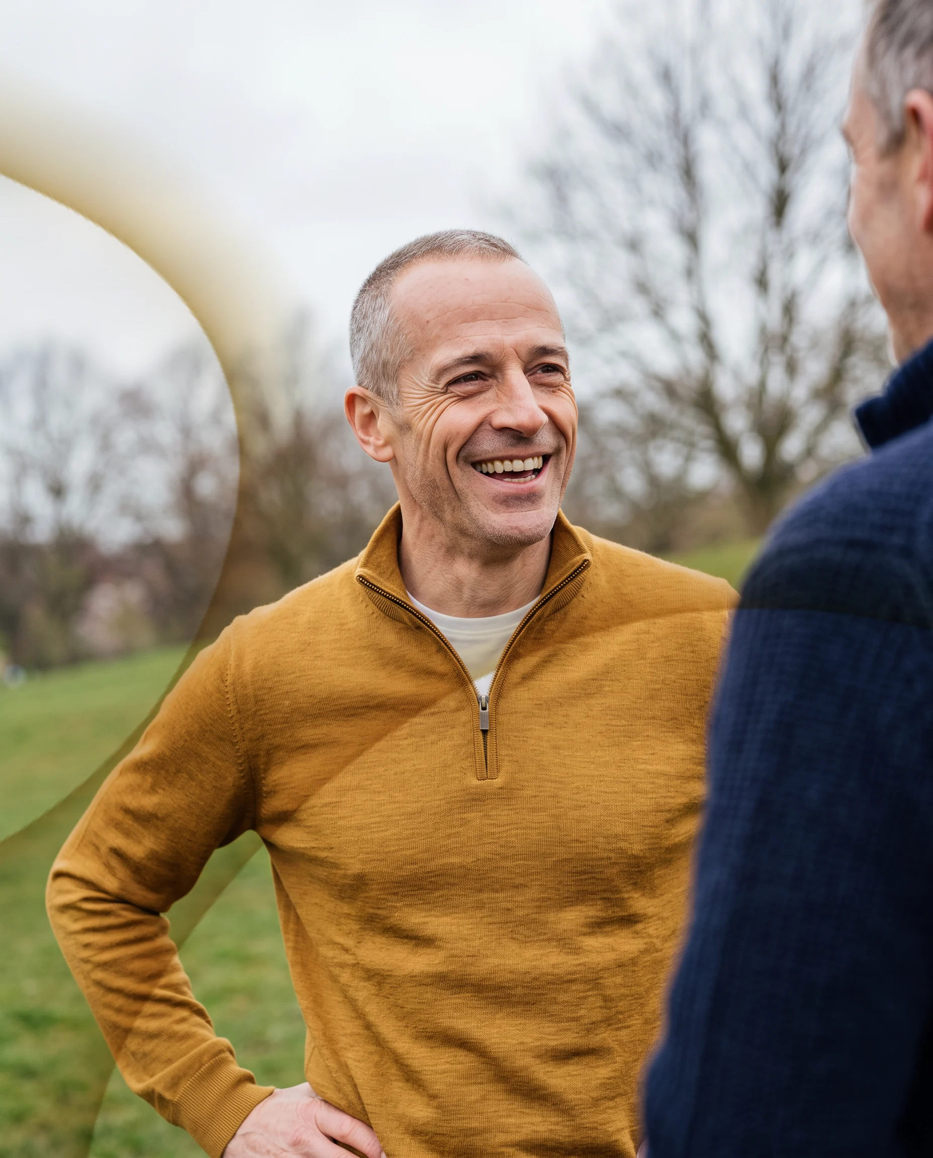 A man in his fifties laughing with a friend on a morning walk
